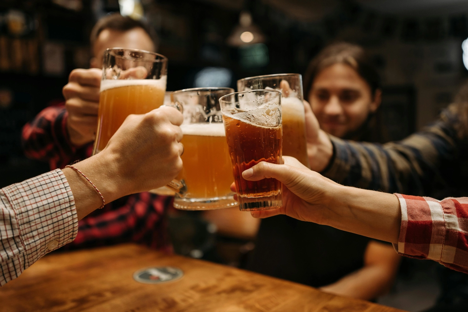 Hygge - Ferienwohnung - Dieses Bild fängt ein fröhliches Treffen von Freunden ein, die gemeinsam Bierflaschen anstoßen.